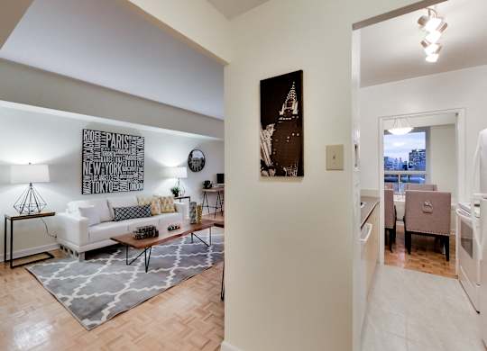 A living room with a white couch and a large painting of the Eiffel Tower.