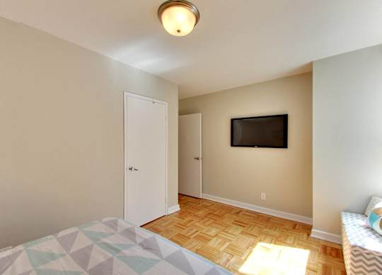 a bedroom with a tv on the wall and a bed