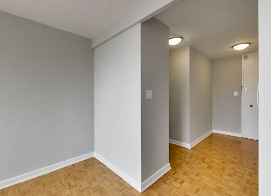 an empty living room with wood flooring and grey walls
