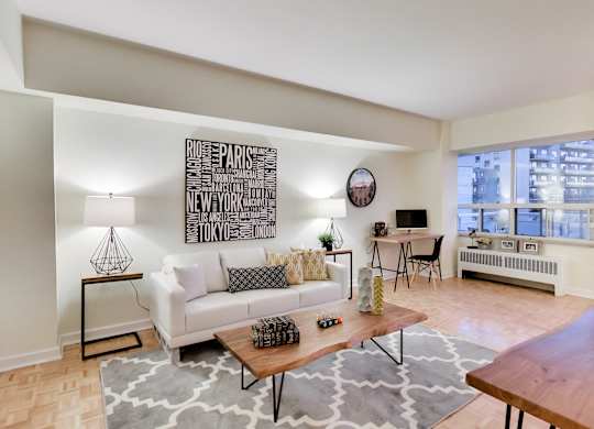 A living room with a white couch and a large artwork on the wall.