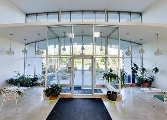 a living room with glass doors and potted plants