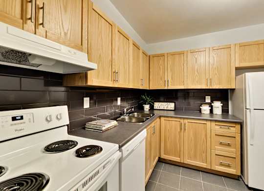 A kitchen with wooden cabinets and a white stove.