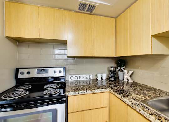 A kitchen with a stove, sink and counter.