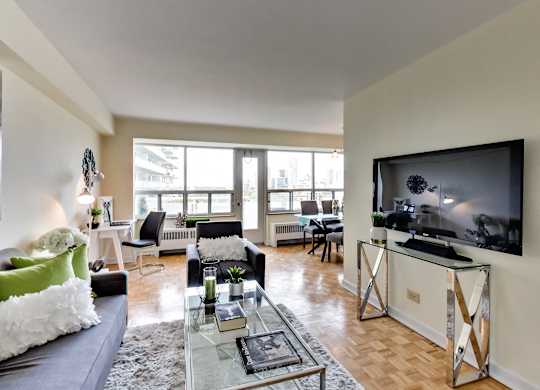 A living room with a television and a glass coffee table.