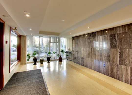 A hallway with a brown marble wall and a grey carpet.