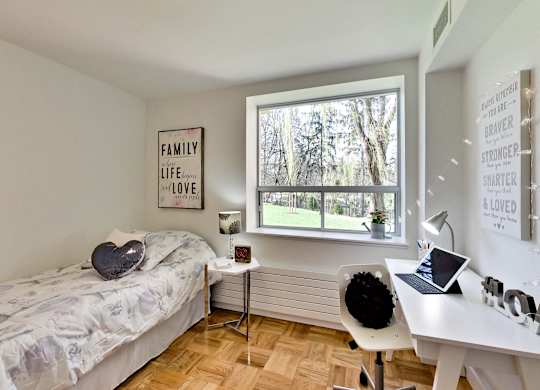 a bedroom with a bed and a desk and a window
