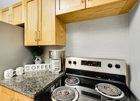 A coffee maker is on a counter next to a stove.