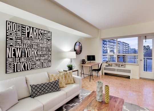 A living room with a white couch and a word art on the wall.
