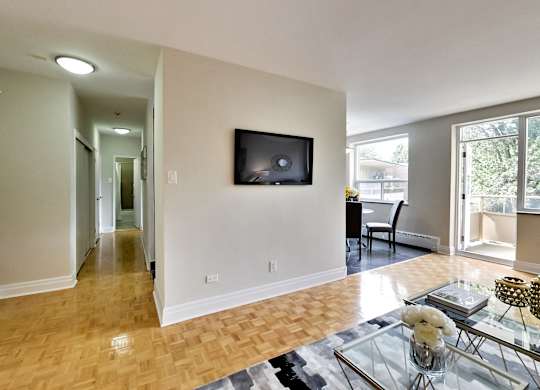 a living room with a tv on the wall and a glass table
