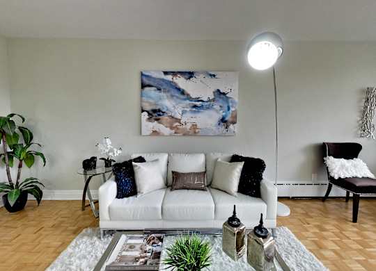 a living room with a white couch and a painting on the wall