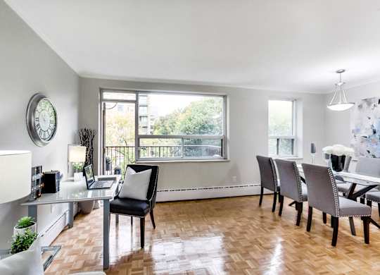 a living room with a dining room table and chairs and a large window