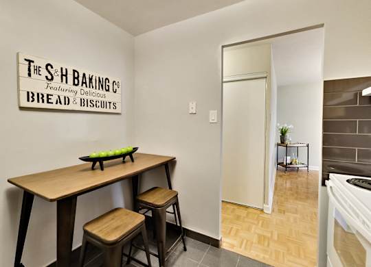 A bakery with a wooden table and stools is set up in a room.