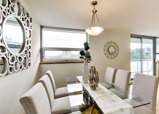 A modern dining room with a glass table and chairs.
