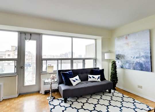 A living room with a grey couch and a large painting on the wall.
