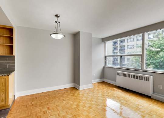 an empty living room with a kitchen and a large window
