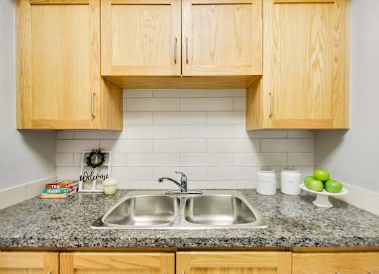 A kitchen with a granite countertop and wooden cabinets.