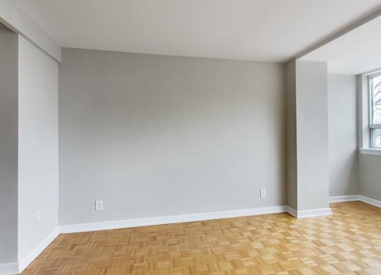 an empty living room with wood flooring and a window
