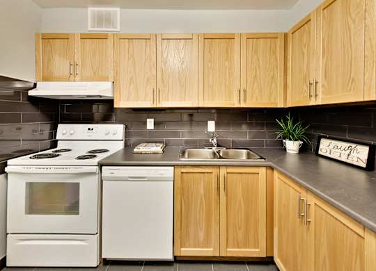 A kitchen with wooden cabinets and a white stove top oven.