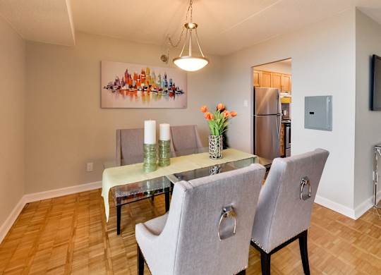 a dining room with a glass table and chairs and a kitchen with a refrigerator