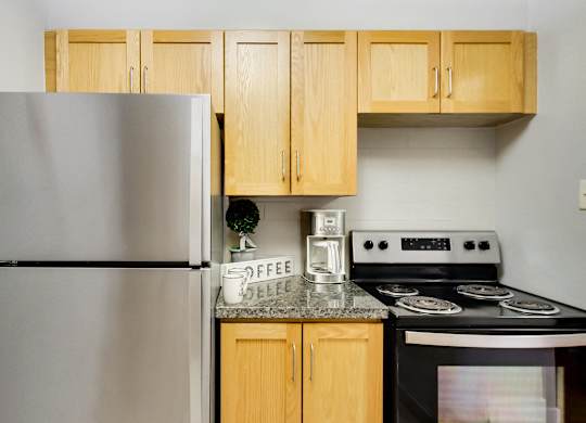 A kitchen with a stove, refrigerator, and cabinets.