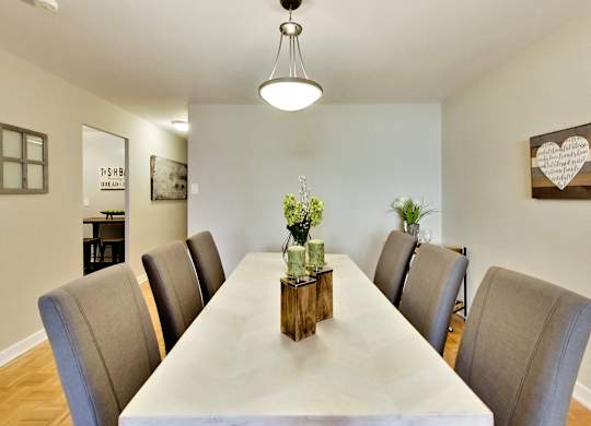 A long table with chairs and a vase of flowers on top.