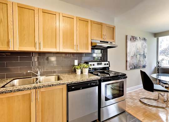 an apartment kitchen with stainless steel appliances and wooden cabinets