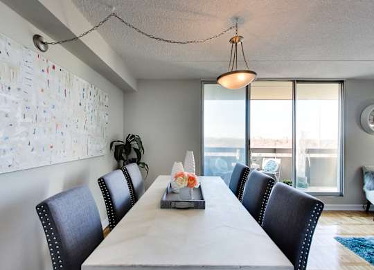 a long dining room table with black chairs and a large window