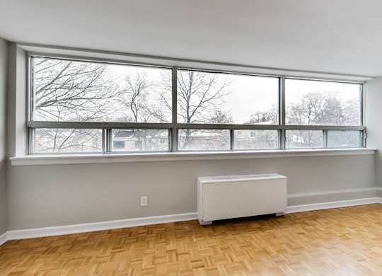 an empty living room with a large window and a radiator
