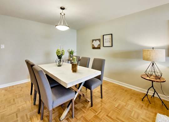 A dining room with a white table and grey chairs.
