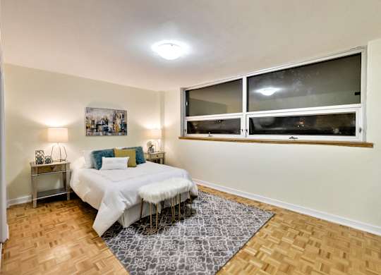 A bedroom with a bed, nightstands, and a window.