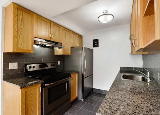 a kitchen with granite countertops and stainless steel appliances and wooden cabinets