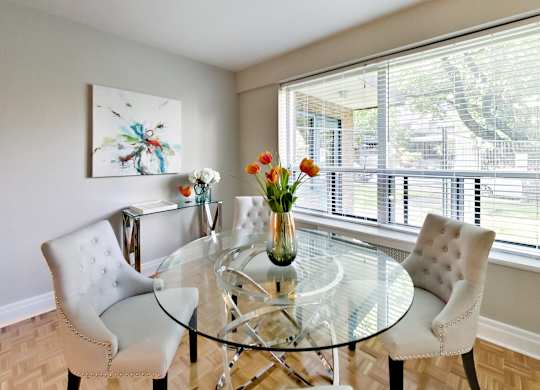 a dining room with a glass table and chairs and a large window