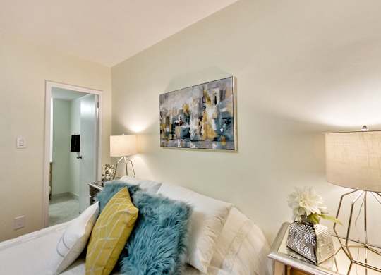 A living room with a white couch and a painting on the wall.