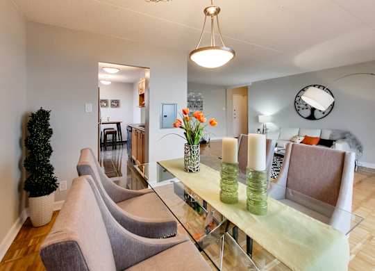 a living room with a glass table with chairs and a dining room table with flowers