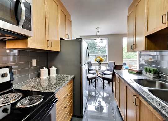 a kitchen with stainless steel appliances and wooden cabinets and a table with chairs
