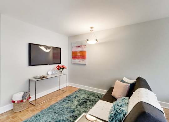 A living room with a grey couch and a television on the wall.
