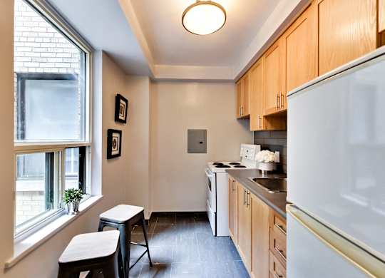 a kitchen with wooden cabinets and a window and a white refrigerator