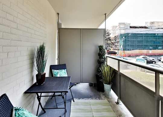 A balcony with a table and chairs overlooking a street.