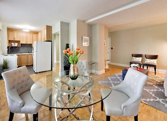a living room with a glass table and chairs and a kitchen