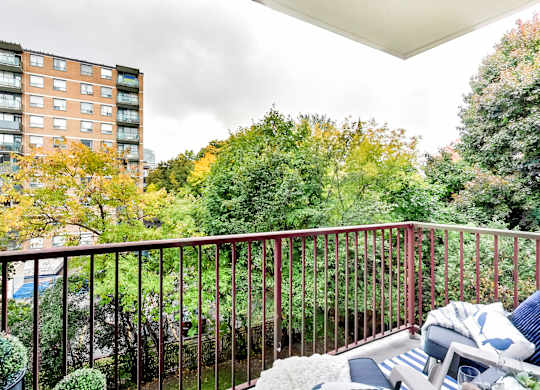 a balcony with a couch and chairs and a view of a garden