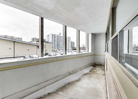 an empty apartment balcony with large windows and a city view