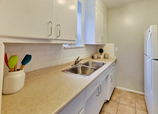 a kitchen with white cabinets and a sink and a refrigerator