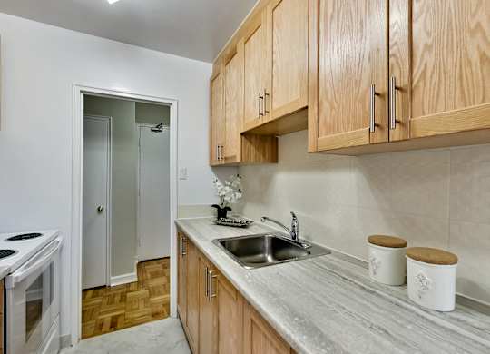 a kitchen with a sink and wooden cabinets and a door to a hallway
