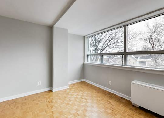 an empty living room with a large window and wood flooring