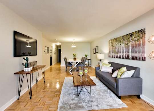 A living room with a grey couch, a coffee table, and a painting on the wall.
