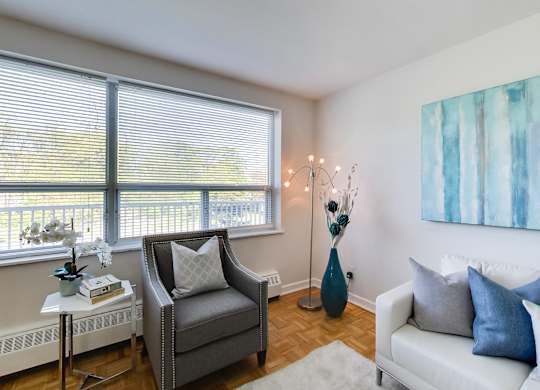 a living room with a couch and a chair and two windows
