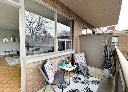 a small balcony with two chairs and a table and a window