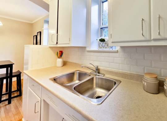a kitchen with a stainless steel sink and white cabinets