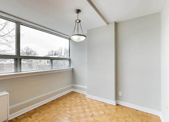 an empty living room with a large window and wood flooring