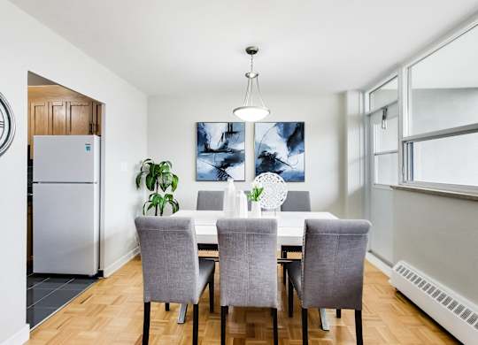 a dining room with a white table and chairs and a refrigerator